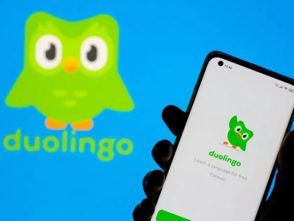 Woman with her smartphone poses in front of displayed Duolingo logo in this illustration taken best international travel apps for travelers from UAE - Duolingo
